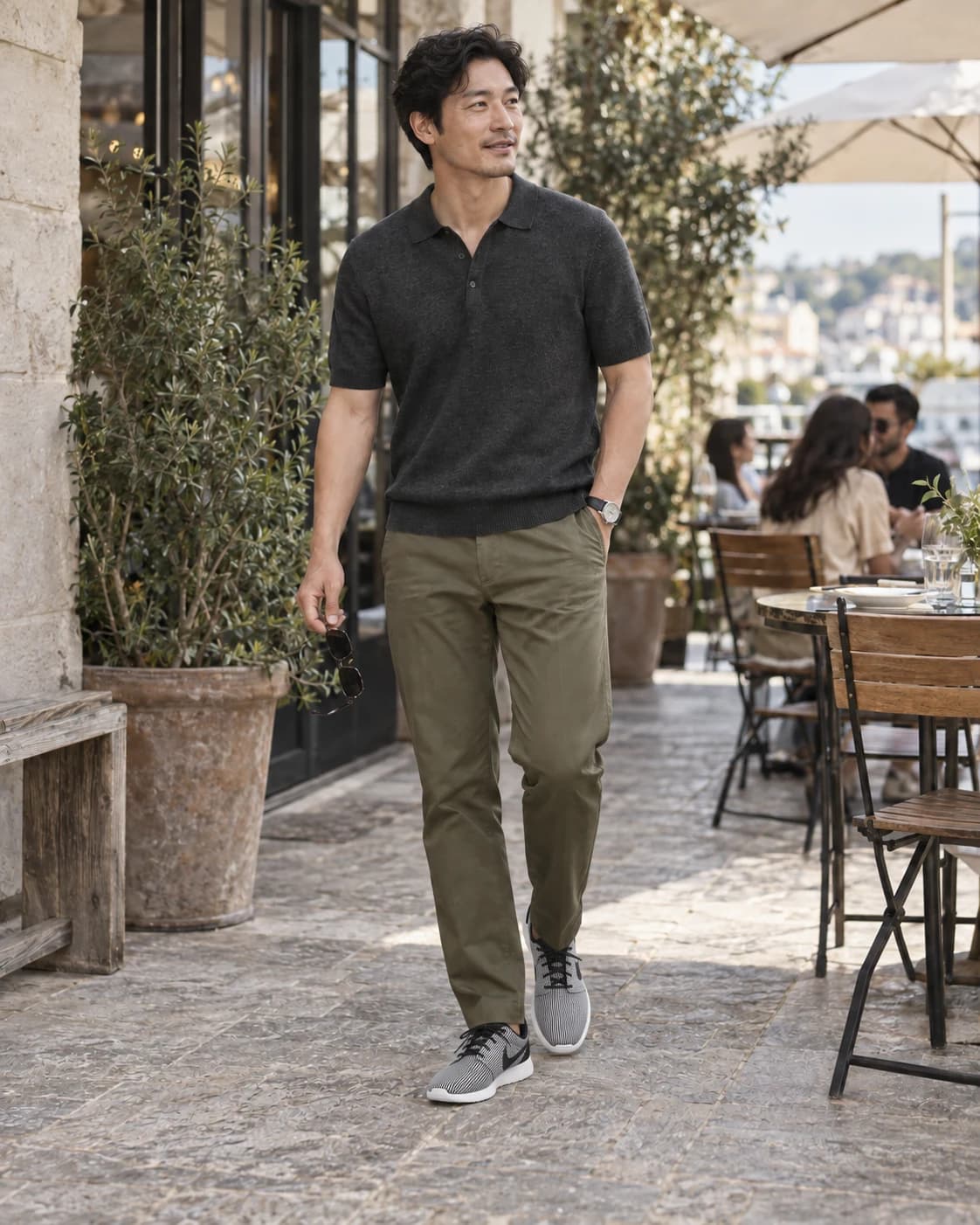 Charcoal knit polo and olive chinos with white-and-black Nike Roshe One Prem Plus low tops on an adult man at an outdoor lunch spot