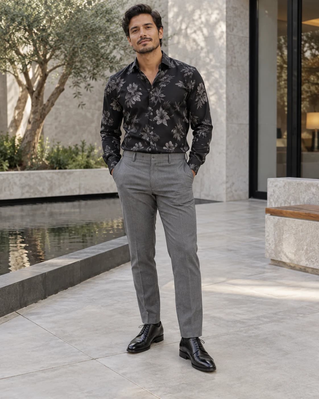 Black long-sleeve shirt with muted gray floral foliage, medium-gray trousers and black leather cap-toe Oxford shoes in a modern courtyard