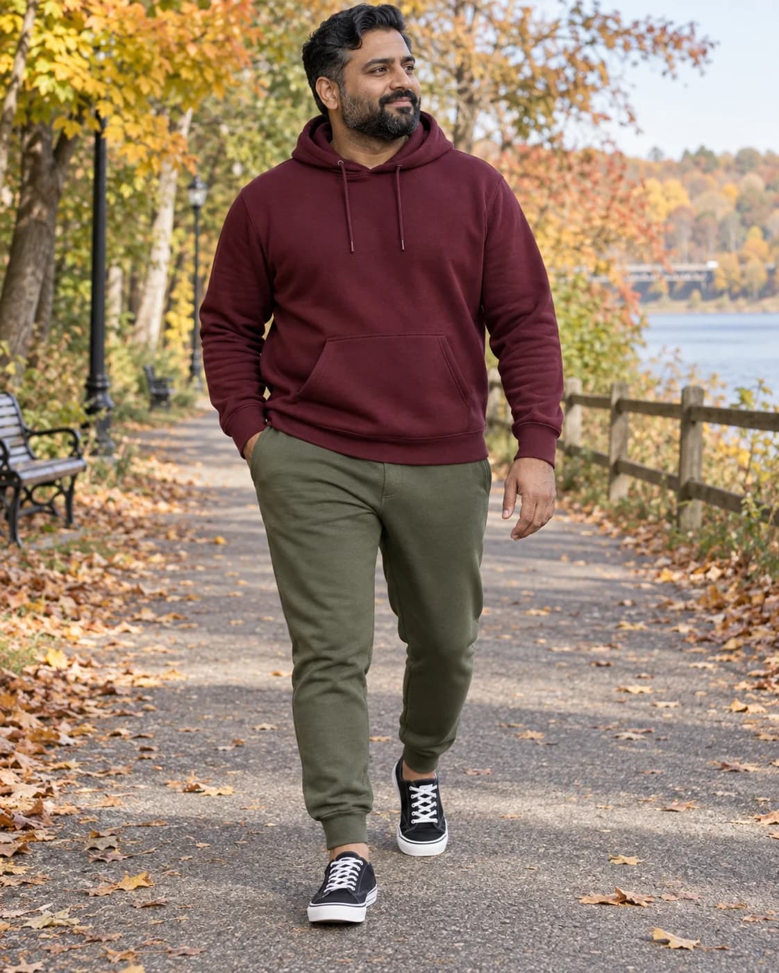 South Asian man in olive joggers, a burgundy hoodie and black low-top canvas sneakers