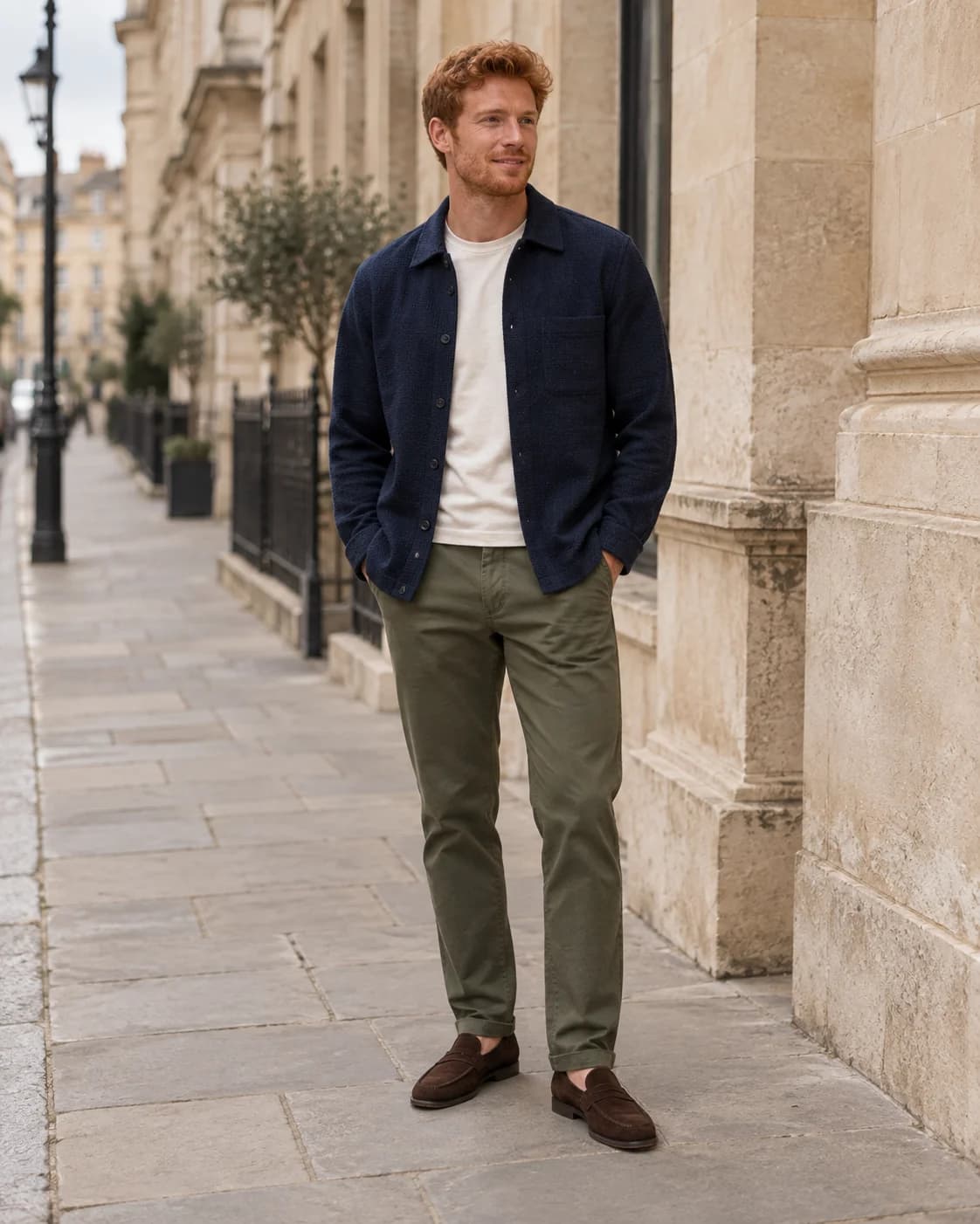 Red-haired man wearing a navy overshirt, ivory T-shirt, olive chinos and brown loafers