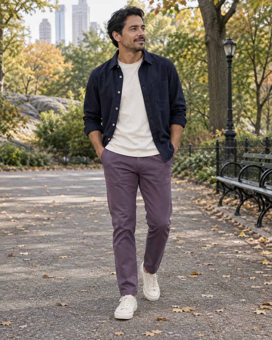 Latino man wearing purple chinos with a cream tee, navy overshirt and off-white trainers on a city walk